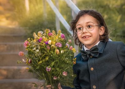 Portrait of smiling kid with wild flower bouquet