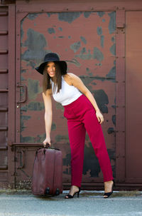 Full length portrait of woman standing against wall