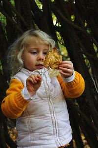 Full length of cute girl holding tree