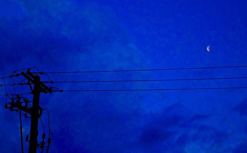 Low angle view of power lines against blue sky