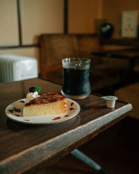 Close-up of black coffe and cake in glass on a cafe table