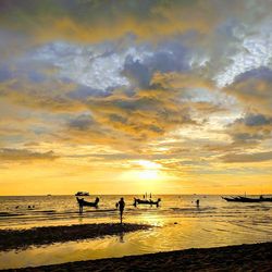 Silhouette people on beach against sky during sunset