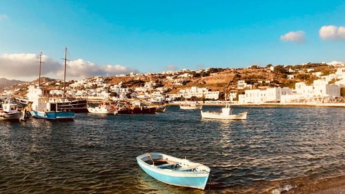 Sailboats moored on sea by townscape against sky