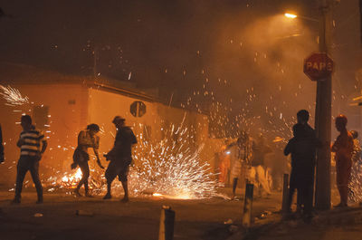 Group of people burning firework in city at night