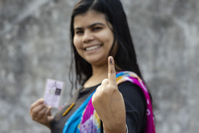 Selective focus on ink-marked finger of an indian woman with smiling face and voter card