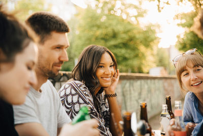 Young female smiling while sitting with friends at social gathering