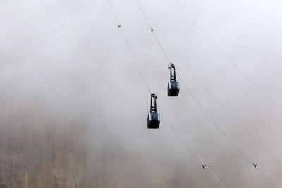 Low angle view of overhead cable car against sky during winter