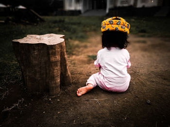 Rear view of girl sitting on wood