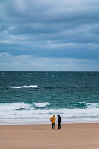 Men standing on beach against sky