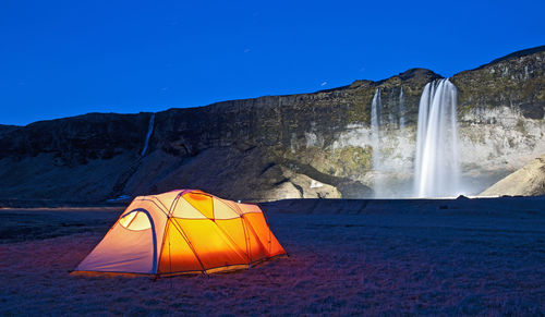 Lit up tent at the waterfall seljalandsfoss in south iceland