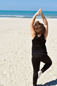 Rear view of girl exercising at beach