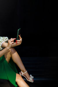 Low section of woman using mobile phone