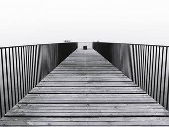 Wooden footbridge on pier against clear sky