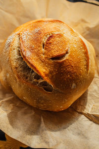 Freshly baked round loaf of homemade sourdough bread on brown parchment paper