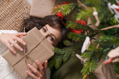 Beautiful girl lies on floor near christmas tree with gift box. magical