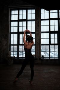 Full length of shirtless man standing in window