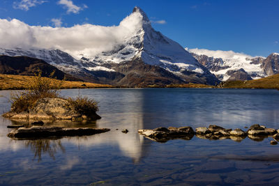 Scenic view of lake by snowcapped mountains against sky