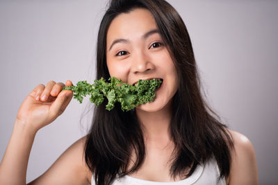 Portrait of young woman holding food against white background