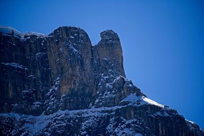 Low angle view of snowcapped mountain against blue sky