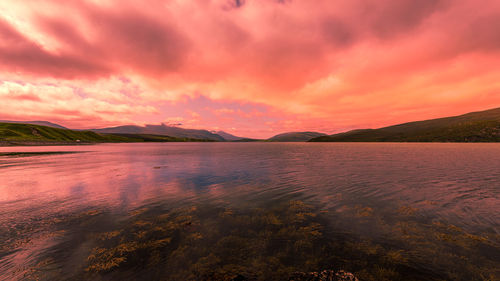 Scenic view of sea against dramatic sky during sunset