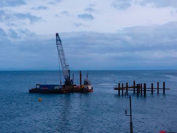 Scenic view of river with rig against sky