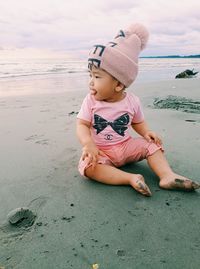 Portrait of cute girl sitting on sand at beach