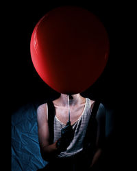 Midsection of person with balloons against black background