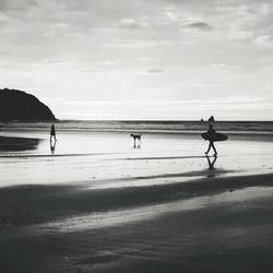 Silhouette people on beach against sky