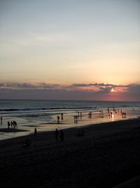 People on beach against sky during sunset