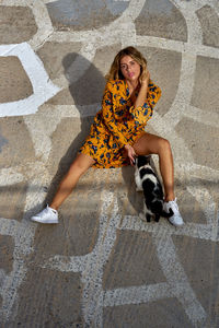 Full length portrait of woman sitting outdoors