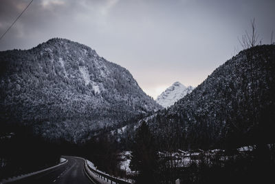 Road by mountains against sky during winter