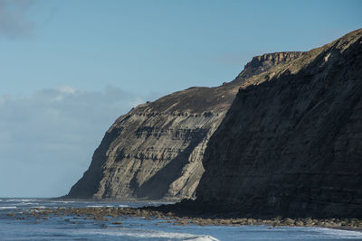 Rock formations by sea against sky