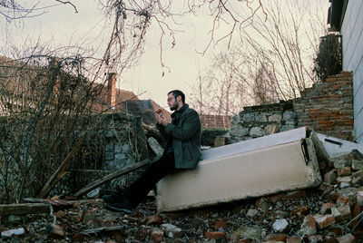 Woman sitting on snow covered bare tree