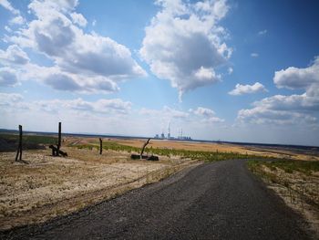 Road amidst field against sky