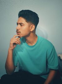 Thoughtful young man looking away against wall