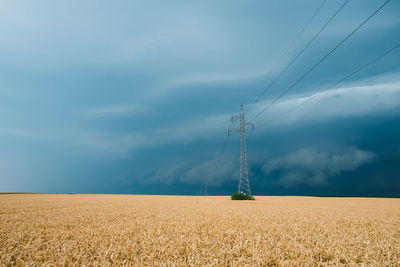 Scenic view of electricity pylon on field against sky