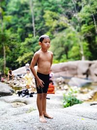 Full length of shirtless boy standing on rock