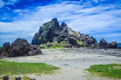 Rock formation on beach against sky