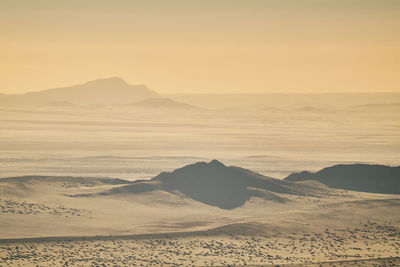 Scenic view of arid landscape against sky during sunset