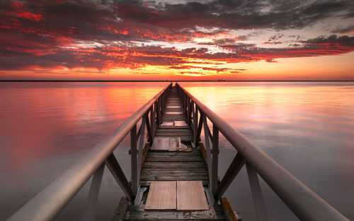 Pier over sea against sky during sunset