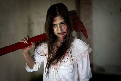 Portrait of young woman with halloween make-up holding axe