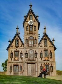 Woman using smart phone while sitting against historic building