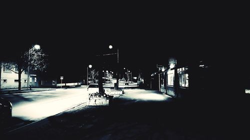 Illuminated street amidst buildings in city at night