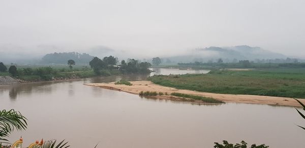 Scenic view of lake by field against sky