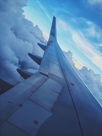 Close-up of airplane wing against cloudy sky