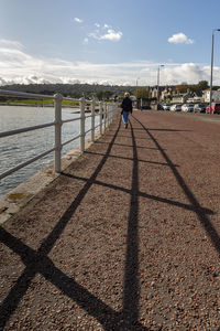 Man on footpath by sea against sky