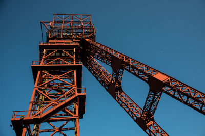 Low angle view of crane against clear blue sky