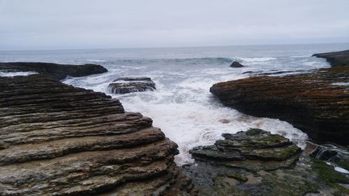 Scenic view of rocky coastline against cloudy sky