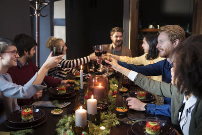 Friends toasting wine while enjoying meal at christmas party