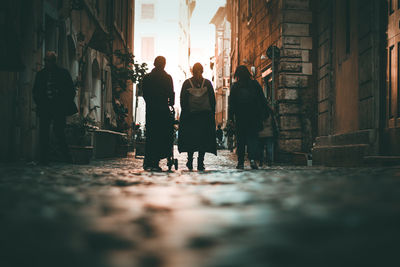 Rear view of people walking on street amidst buildings